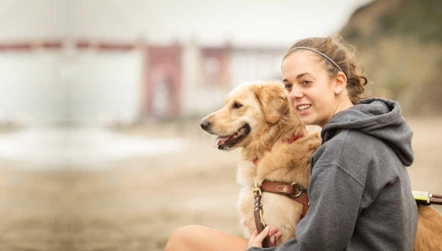 Kvinde sidder udenfor med sin hund i snor ved siden af sig