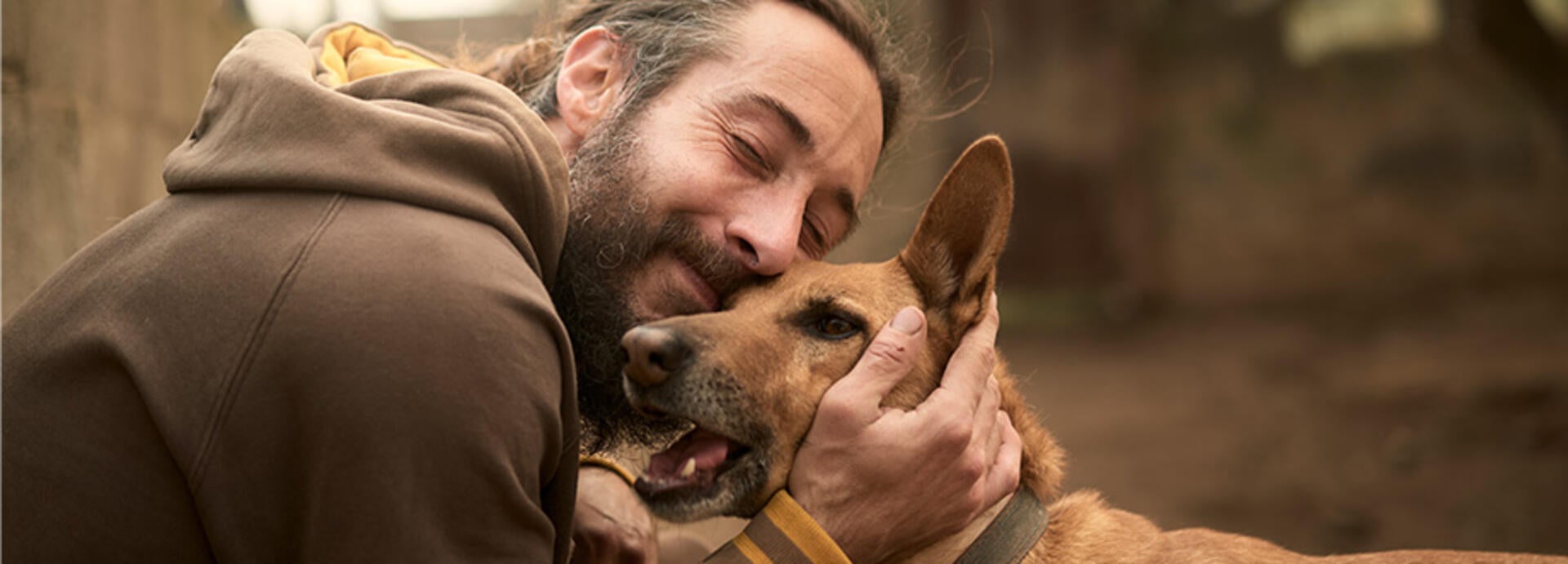 Ejeren giver sin hund et kram.