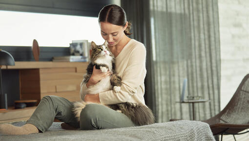 kvinde sidder på sengen og kæler med kat